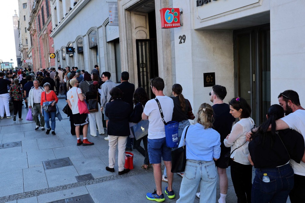 People queue to withdraw cash at an ATM after a massive blackout made paying by credit card impossible, in Madrid on April 28. The power cuts affected the entire Iberian peninsula and parts of southern France. Photo: AFP